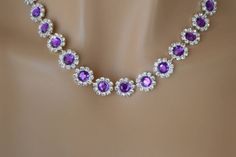 a necklace with purple and white stones on top of a mannequin headdress