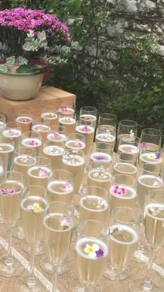 there are many wine glasses on the table with flowers in them and one is empty