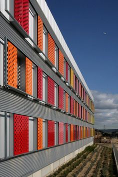 the side of a building with red, orange and grey panels on it's sides