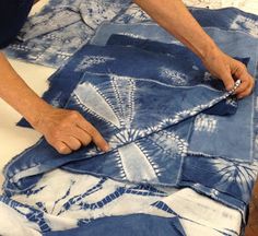 a person that is cutting up some fabric on a piece of blue and white cloth