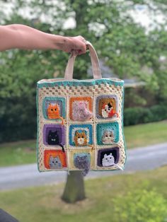 a hand holding a crocheted bag with cats and kittens in squares on it