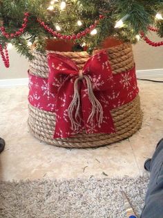 a small christmas tree in a basket with red and white ribbon tied around the top