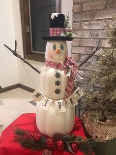 a snowman sitting on top of a table next to a christmas tree