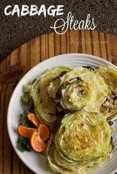 a white plate topped with lettuce and oranges on top of a wooden table