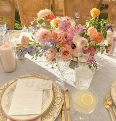 the table is set with plates, silverware and flowers