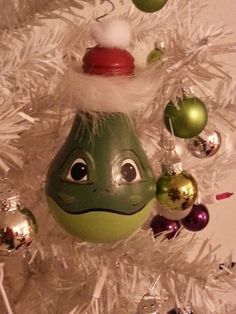 an ornament hanging from the top of a christmas tree with ornaments around it