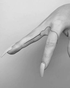 a black and white photo of a person's hand with a finger tattoo