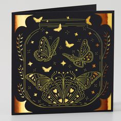 a black card with gold foil butterflies in a glass jar on top of the card