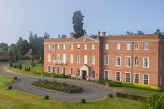 an aerial view of a large red brick building with gardens and trees around the perimeter