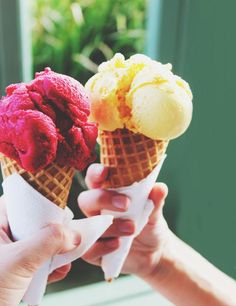 two people holding ice cream cones in their hands