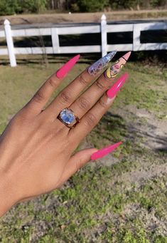 a woman's hand with pink and yellow nail polish on it, holding onto a white fence