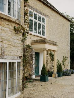 a stone building with two green planters in front of it and a blue door