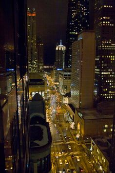 the city is lit up at night with lots of traffic on the street and tall buildings in the background