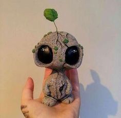 a hand holding a small toy with a plant growing out of it's head