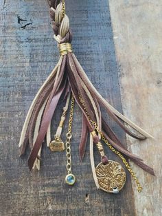 a piece of jewelry is hanging on a wooden board with beads and chains attached to it