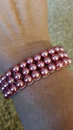 a person wearing a bracelet with pink pearls on it