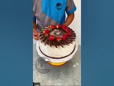 a man holding a cake with strawberries on it