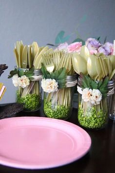 there are many flowers in mason jars on the table next to plates and utensils