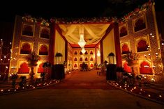 the entrance to a lavishly decorated wedding venue at night with candles lit on the ground