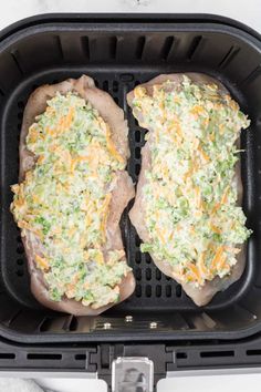 two stuffed mushrooms with cheese and broccoli in a black air fryer pan