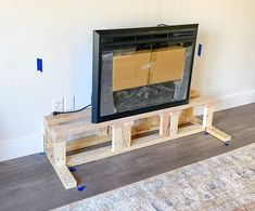 a flat screen tv sitting on top of a wooden stand in a living room next to a rug