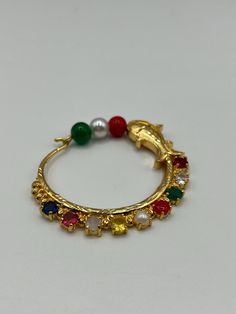 Add an elegant and traditional touch to your hairstyle with this exquisite Gold Plated Navaratna Chandrama Hair Clip.Each gemstone symbolizes prosperity, health, and protection, making this clip both a beautiful and meaningful addition to your collection. The gold plating adds a regal finish, enhancing the timeless appeal of this piece. Whether you're dressing up in a saree or lehenga, this Navaratna hair clip is a perfect complement to complete your traditional look. Bollywood Style Jeweled Tikka As Gift, Elegant Openable Jewelry For Puja, Temple Jewelry Jeweled For Puja, Temple Jewelry For Puja With Jeweled Details, Jeweled Temple Jewelry Tikka As Gift, Jeweled Jewelry For Diwali Puja, Festive Gemstone Jewelry For Puja, Shanku Chakra Namam, Gold Plating