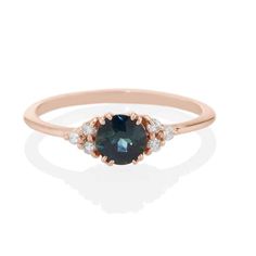 an oval blue sapphire and diamond ring with two diamonds on the band, set in rose gold