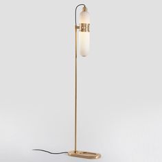 a floor lamp with a white glass shade on the top and a gold metal base