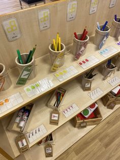 several cups with pens, pencils and markers are on the shelf next to each other