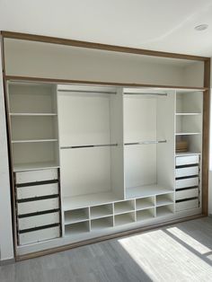 an empty room with white shelves and drawers on the wall, in front of a window