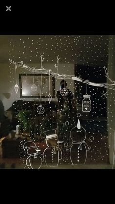 a christmas scene is drawn on the glass in front of a window with snowflakes