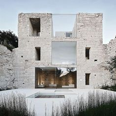 the building is made out of stone and has glass doors on each side that lead to an outdoor swimming pool