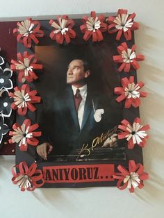 a man in a suit and tie with red flowers on it is framed by black and white paper