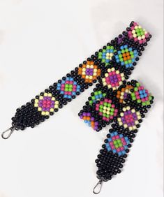 the beaded bracelet is made with black beads and multicolored squares on it