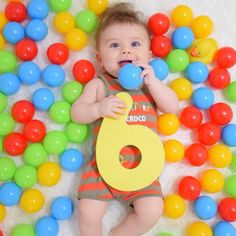 a baby laying on top of a pile of colorful balls