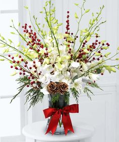 a vase filled with white flowers and greenery