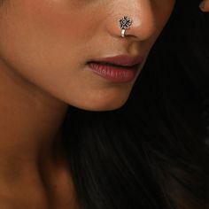 a close up of a woman with a nose piercing on her left side, looking at the camera