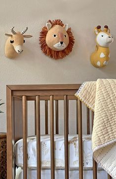 a baby crib with two stuffed animals on the wall above it and another animal head mounted to the wall