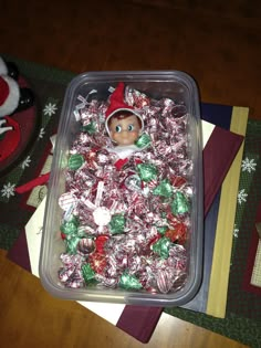 a plastic container filled with candy covered in elf hats