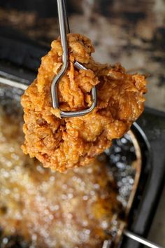 fried food being lifted from a frying pan with tongs to eat the meal