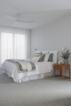 a bedroom with white walls and carpeting has a bed in the middle, two nightstands on either side