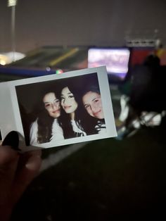 a person holding up a polaroid with two girls on it