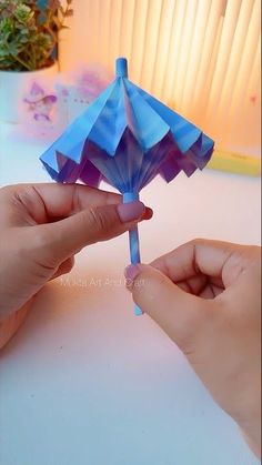 two hands are holding an origami umbrella