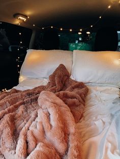 a bed with blankets and lights in the back