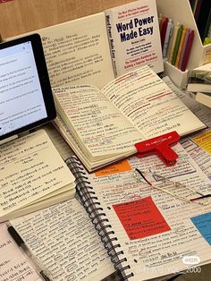 an open notebook with many different types of writing on it next to a tablet computer