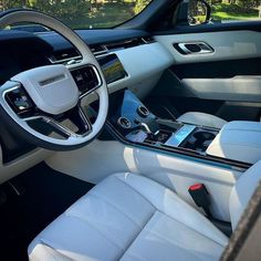 the interior of a car with white leather seats and electronic devices on the steering wheel