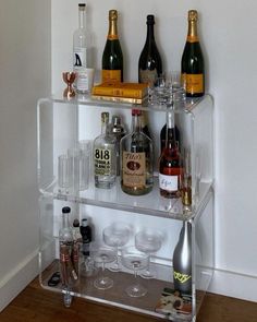 a shelf filled with lots of bottles and glasses on top of a hard wood floor