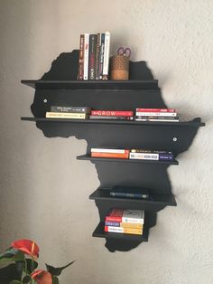 three black shelves with books on them against a wall next to a potted plant