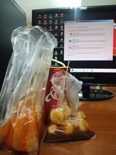 two bags of food sitting next to a computer monitor