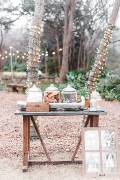 a wooden table topped with lots of food next to palm trees and lights in the background